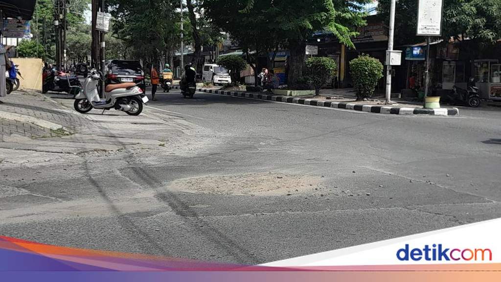 Petugas menutup lubang jalan di persimpangan Jalan Senam Medan dengan pasir dan batu