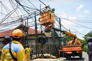 Petugas Pasukan Kuning memperbaiki kabel utilitas yang menjuntai di Jalan Widya Chandra VIII
